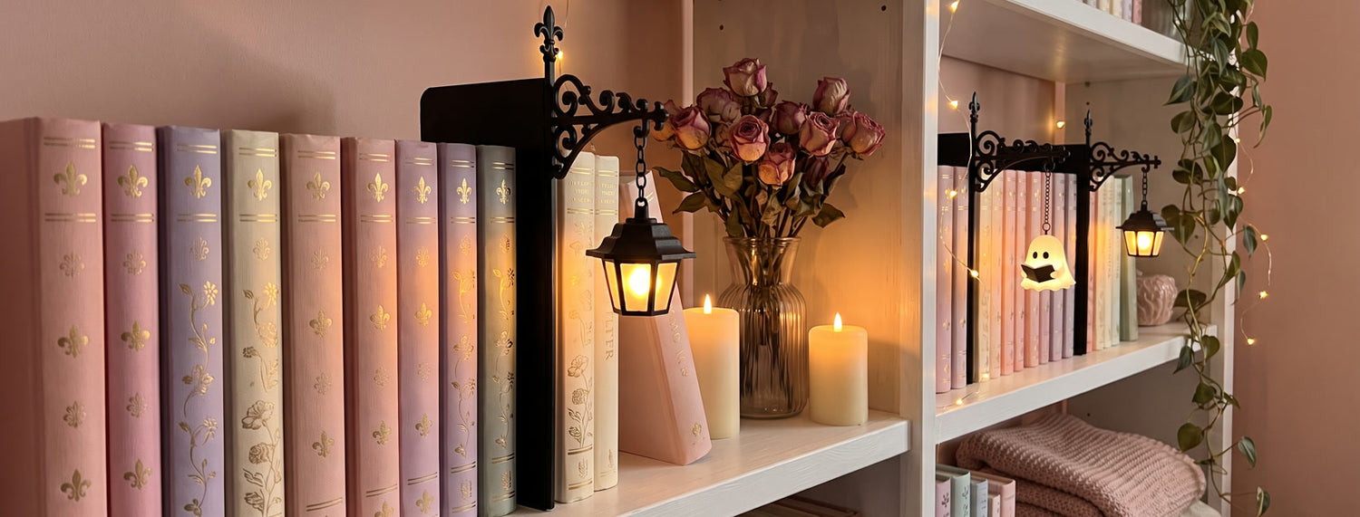 Ember Ink bookshelf lanterns glowing on a pastel shelf