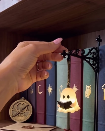 Ghost Reading bookshelf lamp glowing on a walnut shelf of jewel-toned books